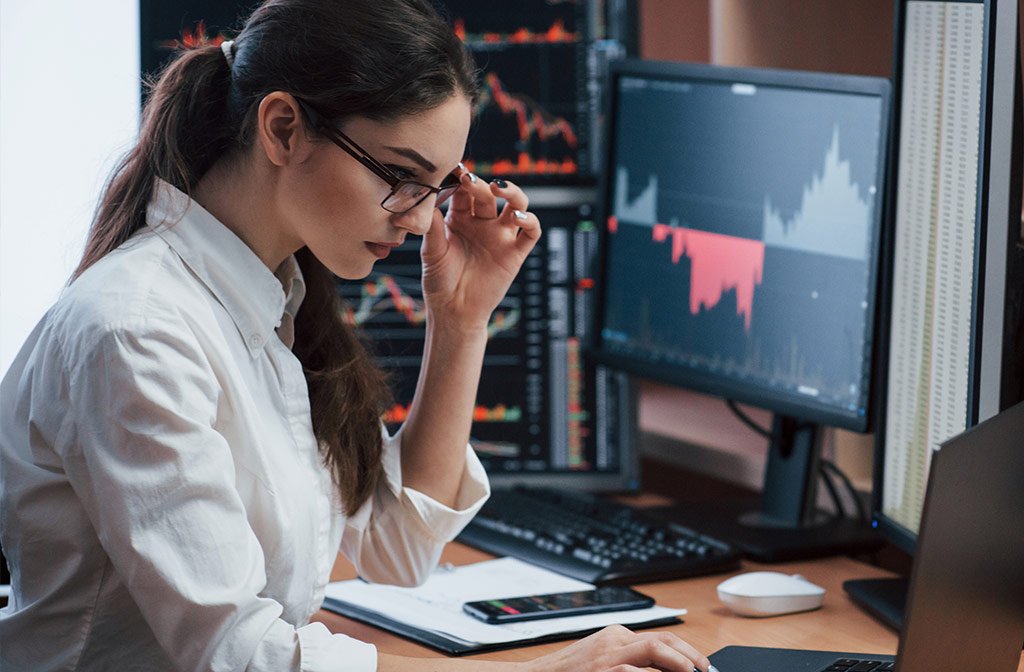 Professionista davanti a più schermi con dati e grafici di gestione