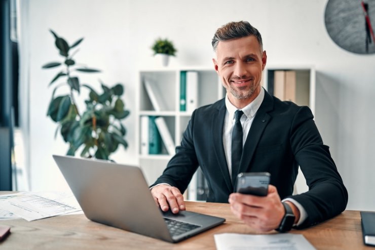 Amministratore al lavoro con computer e smartphone