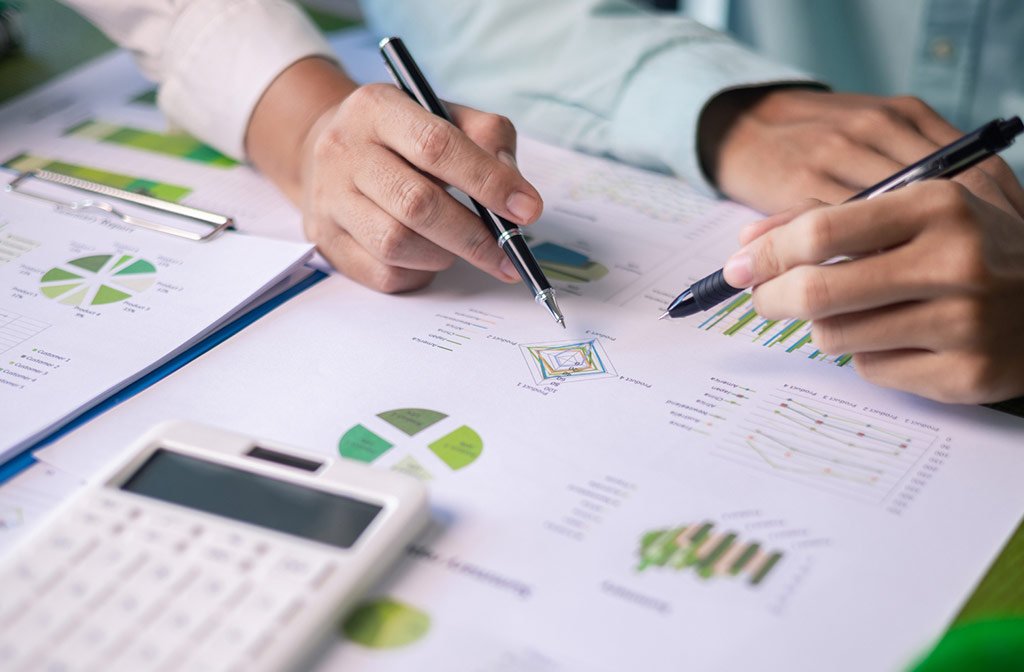 Mani che firmano un contratto energetico accanto a grafici e calcolatrice