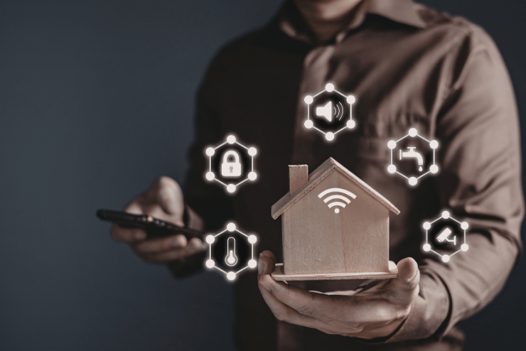 Icone di domotica attorno a un modellino di casa tenuto in mano, soluzioni smart per il condominio